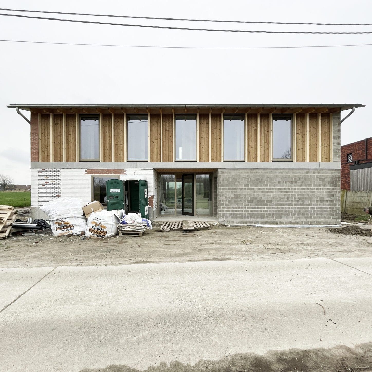 VIJVERHOEK Renovation and extension of a house in rural area, construction site photo of the street facade combining existing and new parament on groundfloor and a wooden facade on first floor